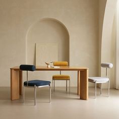 a table with two chairs and a vase on it in a room that has arches