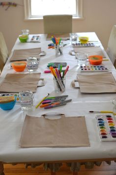 the table is set with art supplies for children to use on their artwork projects, such as crayons and watercolors