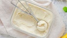 a bowl filled with ice cream next to two bananas and a spoon on a napkin