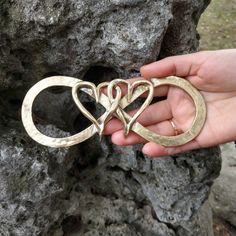 three heart shaped rings are held in the palm of someone's hand near some rocks