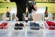 a man standing in front of a table filled with bottles of wine and berries on ice