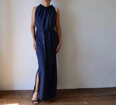 "THIS DRESS IS READY TO SHIP Made of beautiful slinky fabric in midnight blue, this long, elegant grecian style maxi dress is breathtaking. Adding to the beauty of the fabric is the draping, which is created by a delicate row of elastic at the neckline from which the dress falls. Very elegant and feminine in its cut, it falls straight down revealing only a hint of shoulder. The sash belt gently gathers the folds of fabric to accentuate your waist, without adding bulk. It is free of closures, whi Fitted Tie Back Maxi Dress For Wedding Guest, Formal Floor-length Belted Maxi Dress, Wedding Guest Maxi Dress With Tie Back, Belted Floor-length Maxi Dress, Elegant Sleeveless Belted Maxi Dress, Formal Sleeveless Belted Maxi Dress, Elegant Belted Sleeveless Maxi Dress, Elegant Floor-length Tie-waist Dress, Bridesmaid Maxi Length Evening Dress With Tie Back