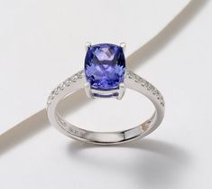 a tan and white gold ring with an oval cut tanzanite surrounded by diamonds