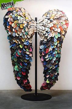 an angel's wings made out of hundreds of different colored buttons on a black stand