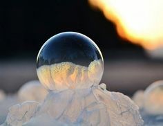 a soap ball sitting on top of snow covered ground with the sun in the background