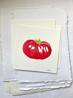 two cards with red tomatoes on them sitting next to each other in front of white paper