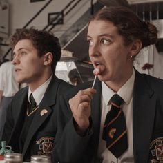 two people sitting at a table with food in front of them and one person sticking out his tongue