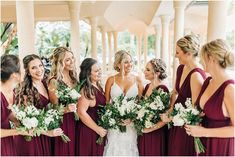 a group of women standing next to each other in front of a building holding bouquets