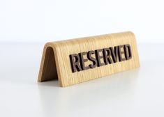 a wooden business card holder with the word reserved printed on it, sitting on a white surface