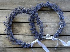 two lavender wreaths tied together on a wooden surface with white ribbons and ribbon around them