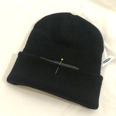 a black beanie with a needle sticking out of it