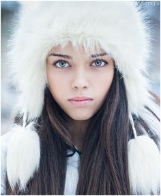 a young woman wearing a fur hat and looking at the camera with an intense look on her face