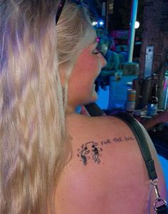 the back of a woman's shoulder with a small tattoo on her left arm