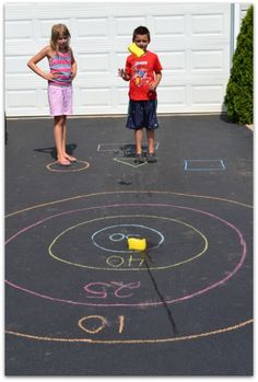 two children standing in front of a driveway with chalk drawings on it