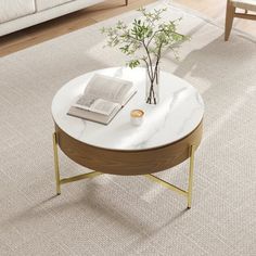 a white marble coffee table with gold legs and an open book on top, in a living room