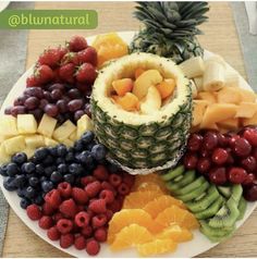 a white plate topped with lots of fruits and veggies next to a pineapple