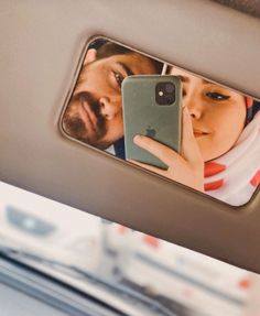 a man and woman taking a selfie in a car mirror with their cell phones