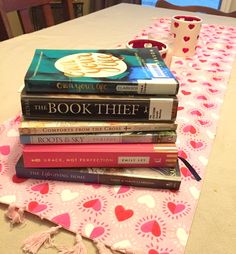 a stack of books sitting on top of a table next to a cup and saucer