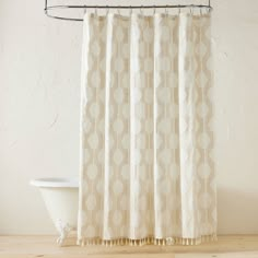 a bath tub sitting next to a shower curtain with circles on it's side