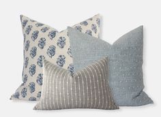 three pillows with different patterns on them, one in blue and the other in white