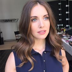 a woman in a blue shirt is posing for the camera