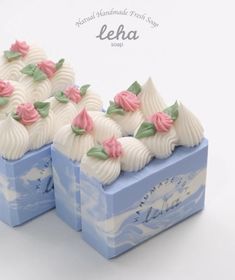 two blue boxes with white and pink frosted desserts on top of each other