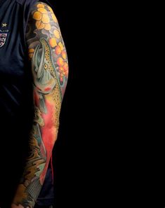 a man with tattoos on his arm and shoulder is standing in front of a black background