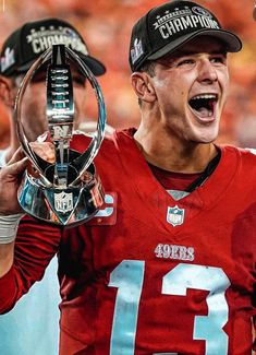 a football player holding up a trophy in front of his face and two other players behind him