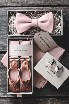 a pink bow tie and matching cufflinks are in a gift box on a wooden table