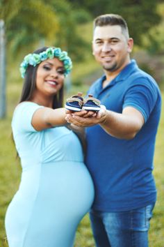 a pregnant couple holding shoes in their hands