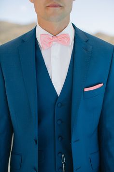 a man wearing a blue suit and pink bow tie