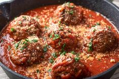 meatballs in tomato sauce with parsley in a black skillet on a table