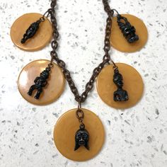 A tikitastic necklace made from 1930's-40's marbelized butterscotch tested bakelite (Catalin) chips with very solid true vintage cast metal tiki gods ☀️🗿☀️🗿☀️🗿☀️ One-off--Repurposed on new plastic chain: I always felt these charms were too awesome to be on a boring skinny black cord in bracelet form.  Most of the tiki faces still have the green sparkly eyes. The figuines have booties 🍑 Please check out the other jewelry in my collection, and message me if you have any specific preferences--I Retro Bakelite Jewelry As Gift, Vintage Amber Resin Jewelry, Handmade Retro Bakelite Jewelry, Vintage Yellow Resin Jewelry, Handmade Round Bakelite Jewelry, Vintage Carved Amber Jewelry, Vintage Amber Carved Jewelry, Vintage Carved Necklace With Round Pendant, Vintage Carved Round Pendant Necklace