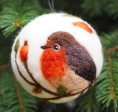 an ornament hanging from a christmas tree decorated with orange and brown felt birds