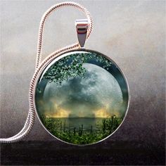 a full moon is seen in the sky behind a tree on a glass pendant necklace