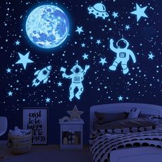 a child's bedroom decorated in blue and white with space themed wall decals