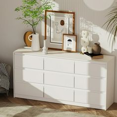 a white dresser with some plants and pictures on it