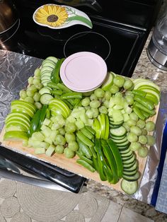 grapes and cucumbers are cut up on a cutting board next to a stove