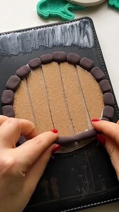 two hands are decorating a cake with chocolate icing and frosting on it