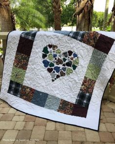 a quilted heart is displayed on a table top with palm trees in the background