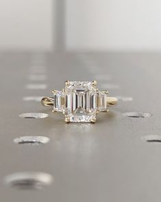 an emerald cut diamond engagement ring on a table