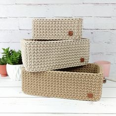 three woven baskets sitting on top of a white table next to a potted plant