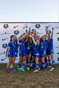 a group of girls soccer players standing next to each other with their hands in the air