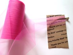 a roll of pink tulle sitting next to a piece of paper on top of a table