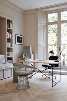 an office with a desk, chair and bookshelf in front of a window