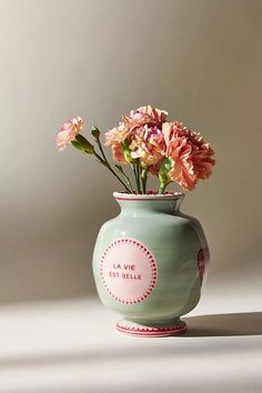 a green vase with pink flowers in it