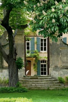 an old stone house with green shutters and trees