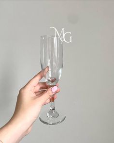 a person holding up a wine glass with the letter m on it