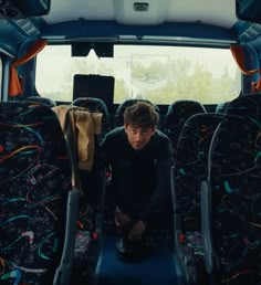 a man sitting in the back of a bus with his feet on the floor and luggage