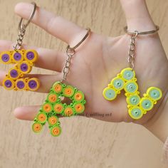 two hand - made key chains with buttons on them are being held by a person's hand